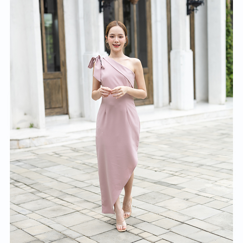 kudapy เดรสยาวสีชมพู/สีครีม/สีน้ำตาลอมส้ม ช่วงบนเป็นแบบปาดไหล่ข้างเดียวแต่งผ้าพับอก มีสายผูกโบว์ที่ไหล่ด้านขวาเพิ่มความหวาน เป็นกระโปรงทรงสอบ กระโปรงชายเฉียงเพิ่มความสวยชิค