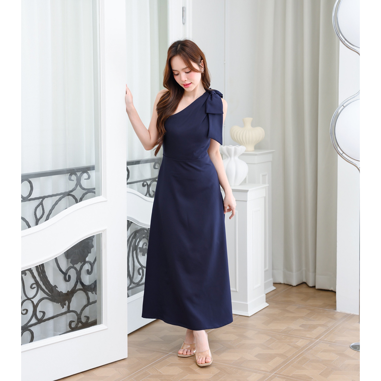 kudapy เดรสยาวสไตล์เรียบหรู ดีไซน์คอเฉีบงปาดไหล่ แต่งด้วยโบว์เพิ่มความน่ารักละมุน ทรงส่วยเข้ารูปพอดีตัว กระโปรงทรงเอยาว