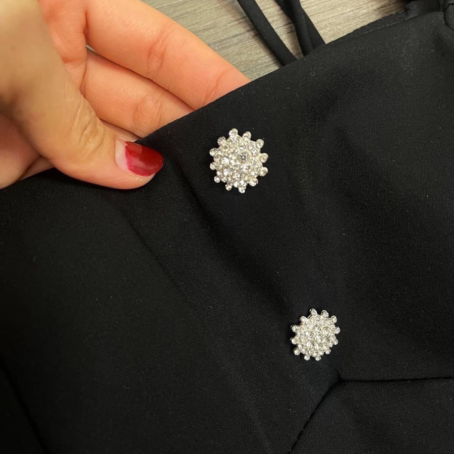 kudapy เดรสสั้นสีดำ คอเหลี่ยมด้านหน้า และหลัง เน้นความเรียบหรู ดูดี แต่งกระดุมเพชรสีเงินด้านหน้า 2 เม็ด ด้านหลังเพิ่มความกิมมิคของชุดออกแบบให้เป็นเชือกผูกเป็นโบว์ได้