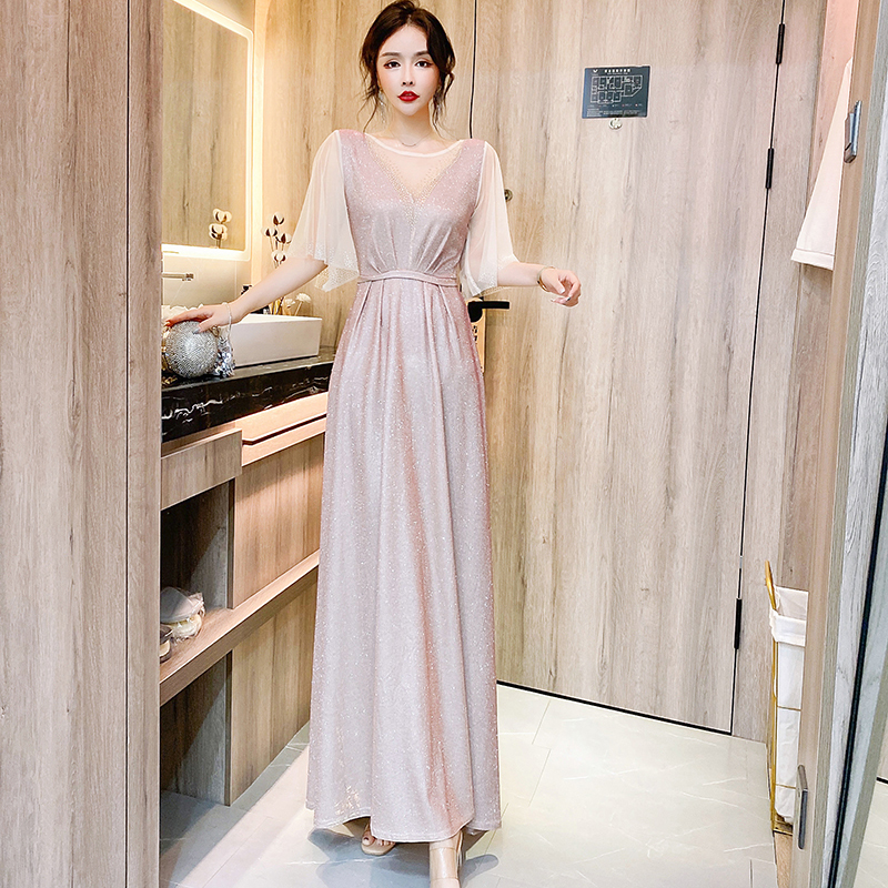 kudapy ชุดราตรียาวสีชมพูอ่อน ผ้ากลิสเตอร์ หน้าอกเสื้อแต่งด้วยผ้ามุ้งสีครีมเป็นตัววี ประดับดิ้นสีทองที่อกเสื้อติดกับผ้ามุ้ง