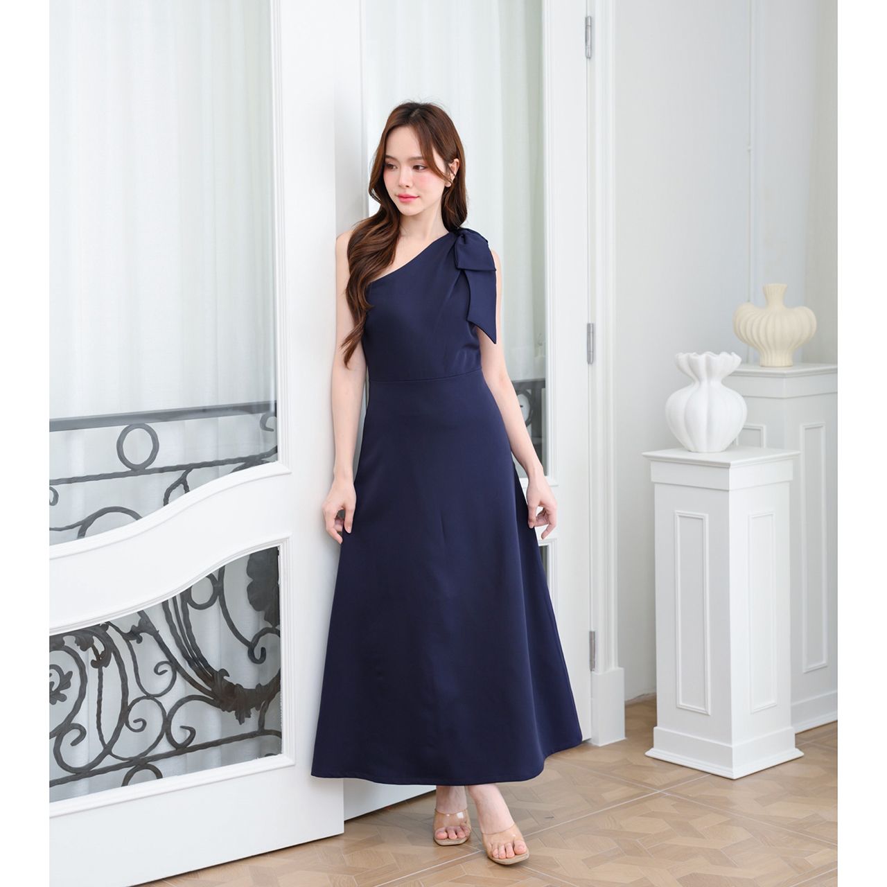 kudapy เดรสยาวสไตล์เรียบหรู ดีไซน์คอเฉีบงปาดไหล่ แต่งด้วยโบว์เพิ่มความน่ารักละมุน ทรงส่วยเข้ารูปพอดีตัว กระโปรงทรงเอยาว