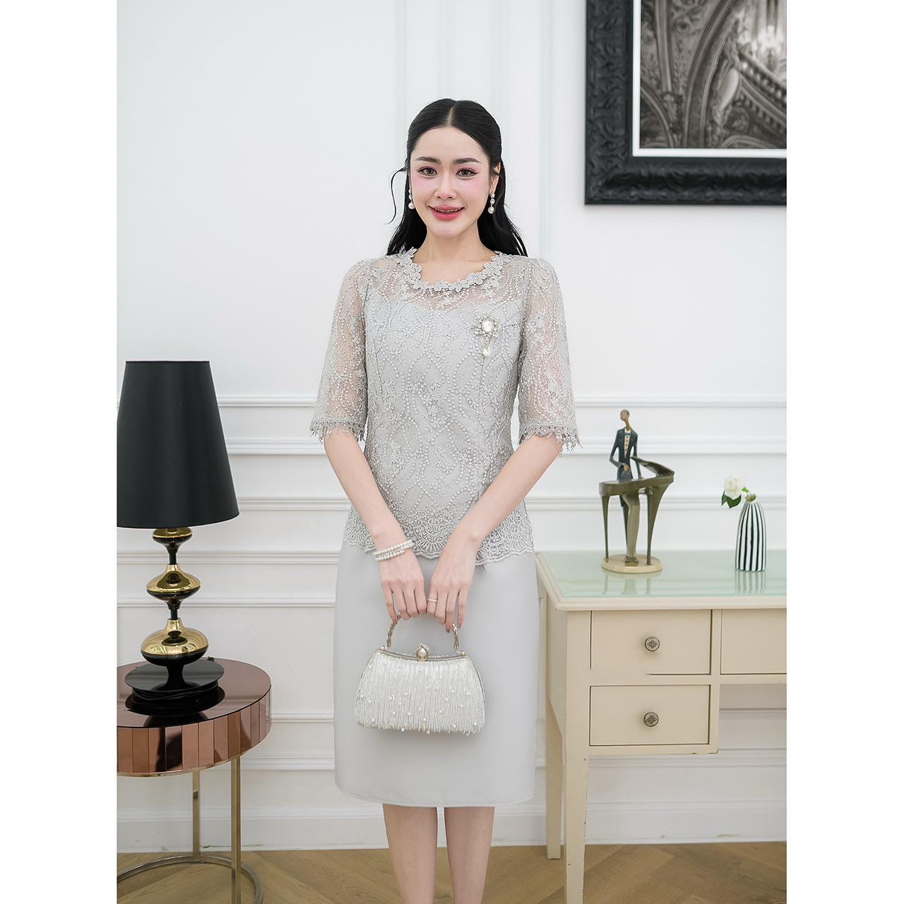 kudapy เดรสผ้าไหมทรงเรียบ ด้านบนเป็นงานผ้าลูกไม้ใยบวบแขนสามส่วนแต่งปลายแขนด้วยลูกไม้ทอลาย ช่วงคอแต่งด้วยลูกไม้ดอกไม้รอบคอ