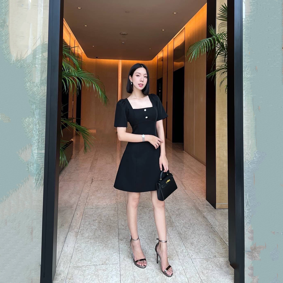 kudapy เดรสสั้นสีดำ คอเหลี่ยมด้านหน้า และหลัง เน้นความเรียบหรู ดูดี แต่งกระดุมเพชรสีเงินด้านหน้า 2 เม็ด ด้านหลังเพิ่มความกิมมิคของชุดออกแบบให้เป็นเชือกผูกเป็นโบว์ได้