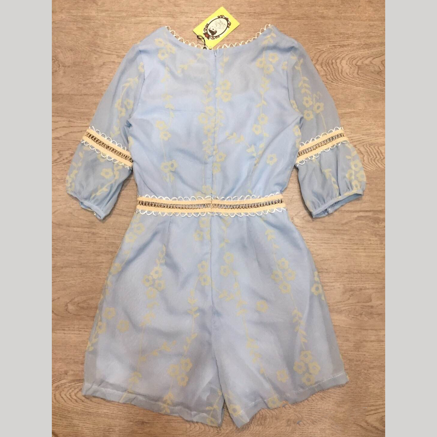 kudapy จั้มสูทขาสั้นสีฟ้าปักลาย คอเหลี่ยม ปลายแขนจั๊ม ตัดต่อด้วยลูกไม้ช่วงแขนและเอว เนื้อผ้าชีฟองพิมพ์ลายรอบตัว มีซับในและซิปหลัง