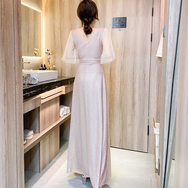 kudapy ชุดราตรียาวสีชมพูอ่อน ผ้ากลิสเตอร์ หน้าอกเสื้อแต่งด้วยผ้ามุ้งสีครีมเป็นตัววี ประดับดิ้นสีทองที่อกเสื้อติดกับผ้ามุ้ง