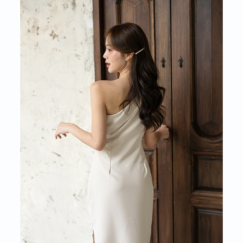 kudapy เดรสยาวสีชมพู/สีครีม/สีน้ำตาลอมส้ม ช่วงบนเป็นแบบปาดไหล่ข้างเดียวแต่งผ้าพับอก มีสายผูกโบว์ที่ไหล่ด้านขวาเพิ่มความหวาน เป็นกระโปรงทรงสอบ กระโปรงชายเฉียงเพิ่มความสวยชิค