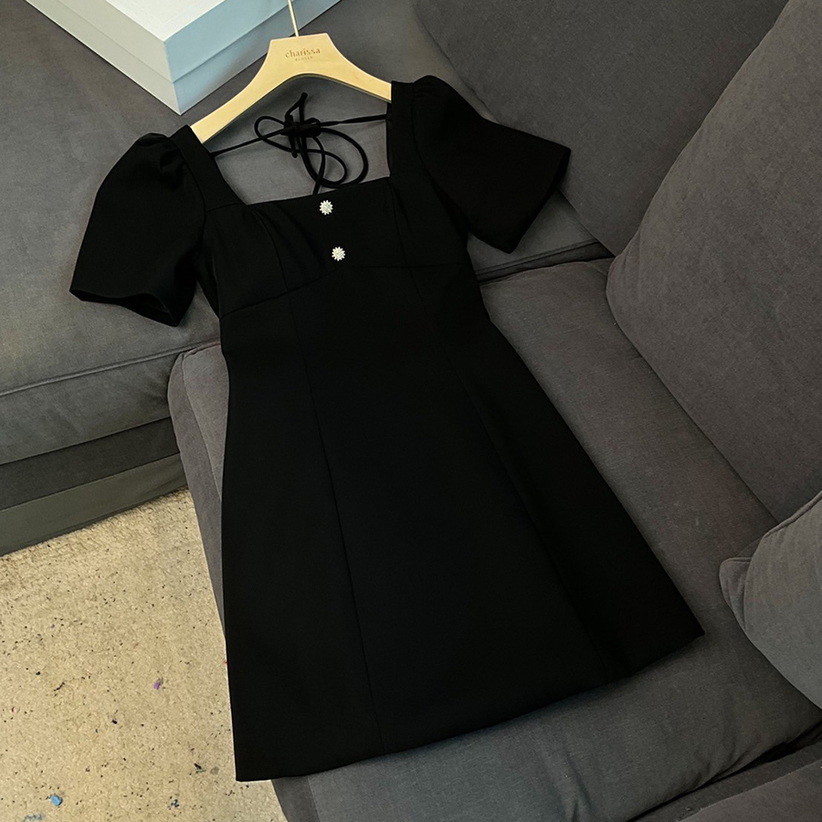 kudapy เดรสสั้นสีดำ คอเหลี่ยมด้านหน้า และหลัง เน้นความเรียบหรู ดูดี แต่งกระดุมเพชรสีเงินด้านหน้า 2 เม็ด ด้านหลังเพิ่มความกิมมิคของชุดออกแบบให้เป็นเชือกผูกเป็นโบว์ได้