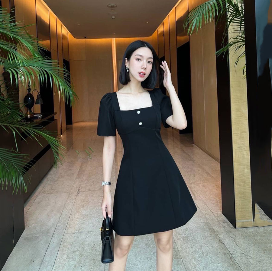 kudapy เดรสสั้นสีดำ คอเหลี่ยมด้านหน้า และหลัง เน้นความเรียบหรู ดูดี แต่งกระดุมเพชรสีเงินด้านหน้า 2 เม็ด ด้านหลังเพิ่มความกิมมิคของชุดออกแบบให้เป็นเชือกผูกเป็นโบว์ได้