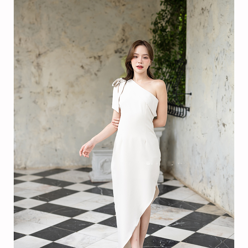 kudapy เดรสยาสีสีน้ำตาลอมส้ม/สีครีม ช่วงบนเป็นแบบปาดไหล่ข้างเดียวแต่งผ้าพับอกดูไม่เรียบจนเกินไป มีสายผูกโบว์ที่ไหล่ด้านขวาเพิ่มความหวาน