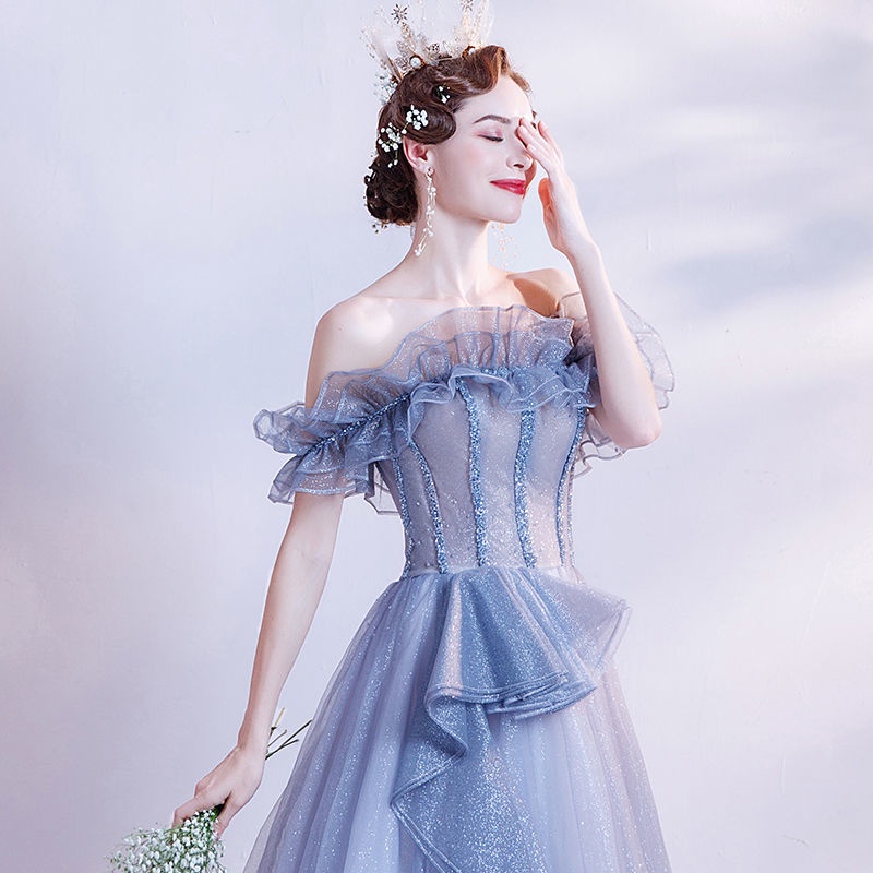 kudapy (พรีออเดอร์ 15-30 วัน) ชุดราตรียาวปาดไหล่ สีฟ้าครามแต่งระบายรอบอก จะจีบช่วงเอวแต่งเป็นเลเยอร์ทิ้งตัวลงมาตามชายกระโปรง ด้านหน้าอกจากเศษผ้าเป็นลายทางงานสวยตามแบบ