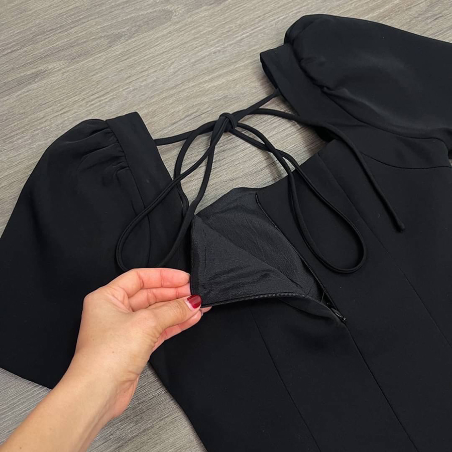 kudapy เดรสสั้นสีดำ คอเหลี่ยมด้านหน้า และหลัง เน้นความเรียบหรู ดูดี แต่งกระดุมเพชรสีเงินด้านหน้า 2 เม็ด ด้านหลังเพิ่มความกิมมิคของชุดออกแบบให้เป็นเชือกผูกเป็นโบว์ได้