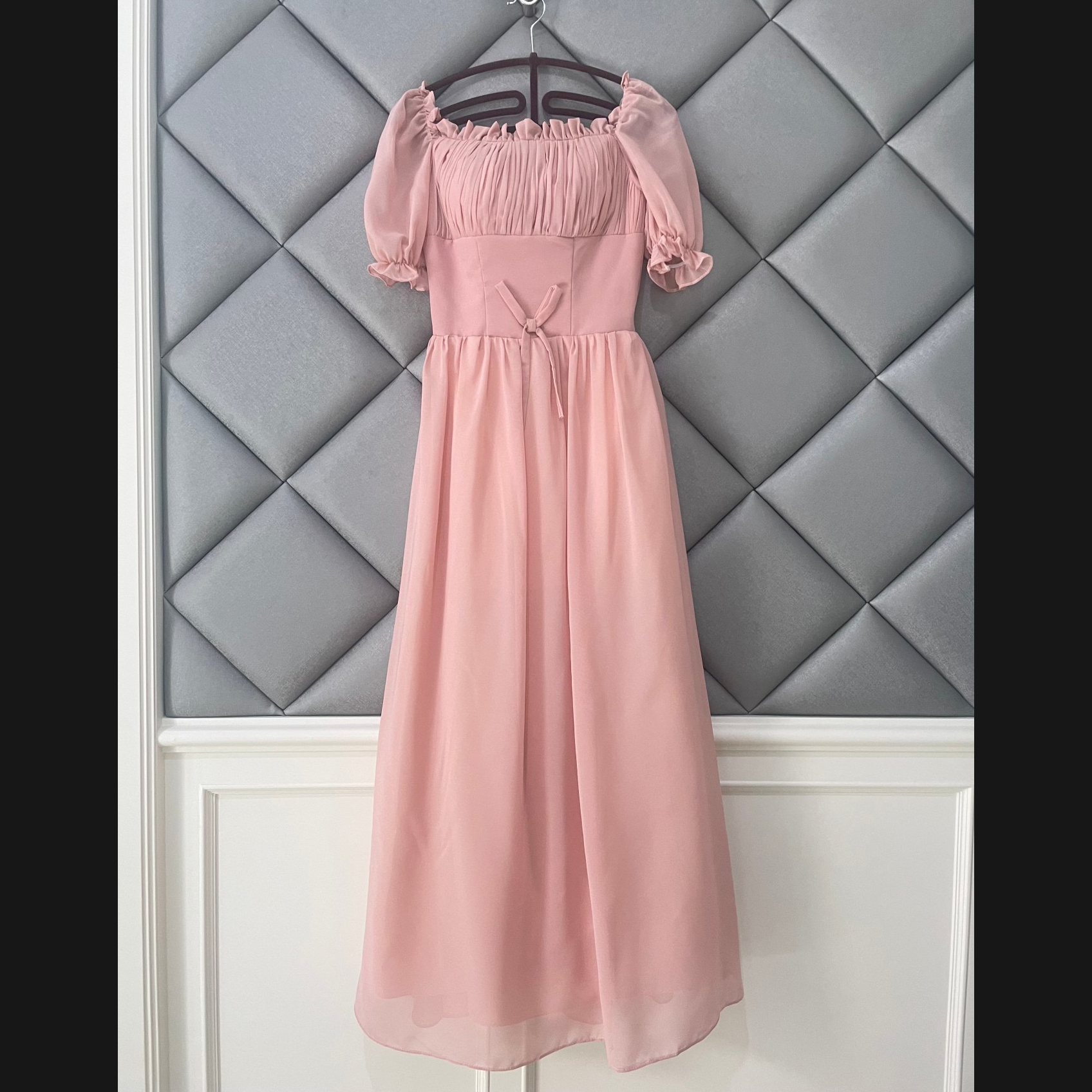 kudapy ชุดเดรสราตรียาว ผ้าชีฟองเนื้อดีสีชมพูนู้ด เดรสเปิดไหล่ หรือปิดไหล่ รอบคอเสื้อมีสายยืดจั๊มด้านใน แขนเสื้อสั้น ปลายแขนจั๊ม เย็บแต่งโบว์ที่เอวด้านหน้า