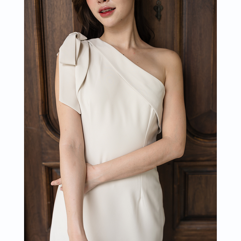 kudapy เดรสยาวสีชมพู/สีครีม/สีน้ำตาลอมส้ม ช่วงบนเป็นแบบปาดไหล่ข้างเดียวแต่งผ้าพับอก มีสายผูกโบว์ที่ไหล่ด้านขวาเพิ่มความหวาน เป็นกระโปรงทรงสอบ กระโปรงชายเฉียงเพิ่มความสวยชิค